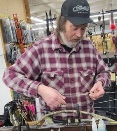 Joel working on a bow in the bow press. Joel working on a bow in the bow press.