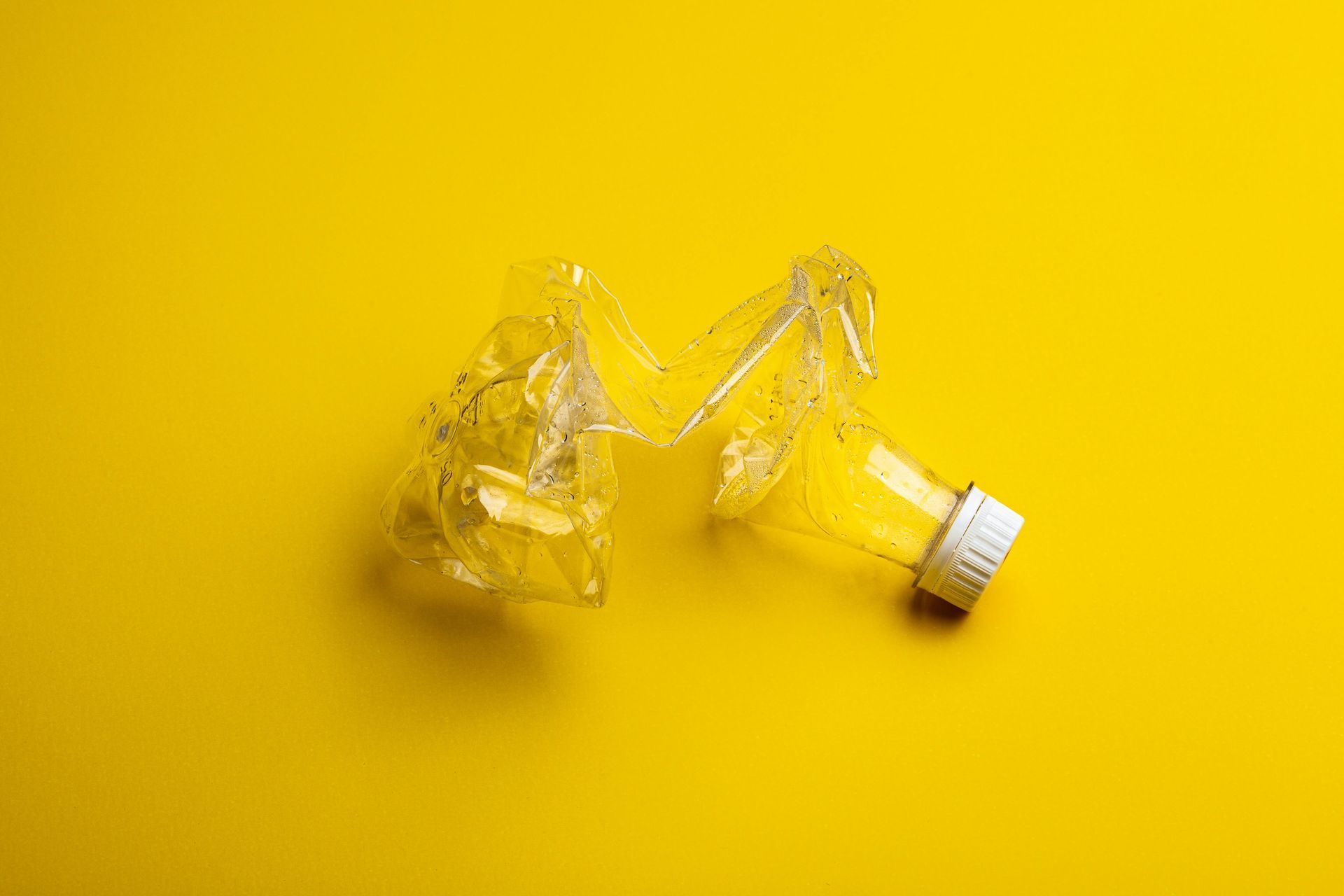 A broken plastic bottle on a yellow background Pinellas Family Junk Removal.