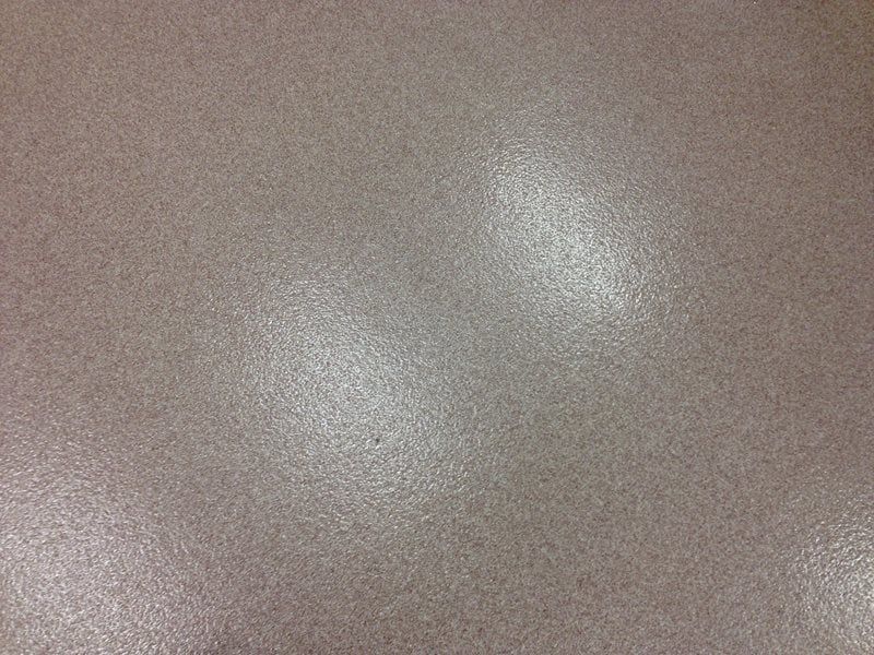 Close-up of a beige textured surface with two soft white reflections.