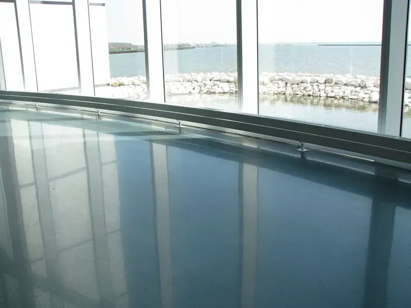 Indoor pool with large windows overlooking a rocky shoreline and the sea