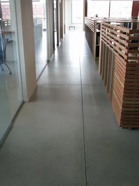 Modern hallway with glass walls, tiled floor, and wooden railing on the right