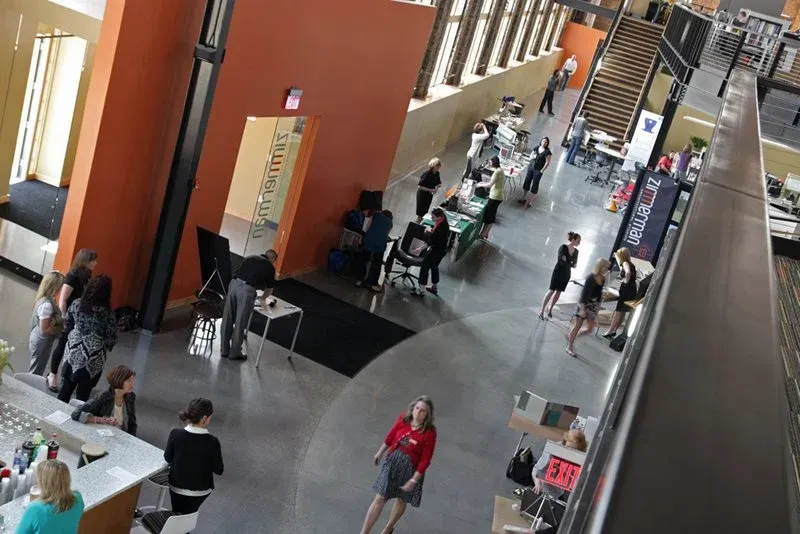 Indoor mall atrium with people walking past shops and tables, viewed from above
