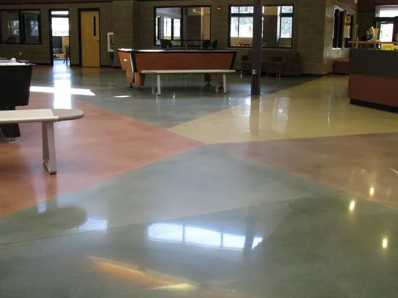 Empty indoor hall with glossy multicolored floor, tables, and vending machines in the background
