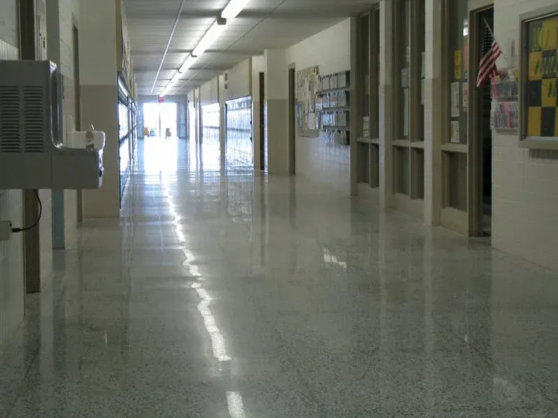 Empty school hallway with lockers, windows, and bright light reflecting on the floor