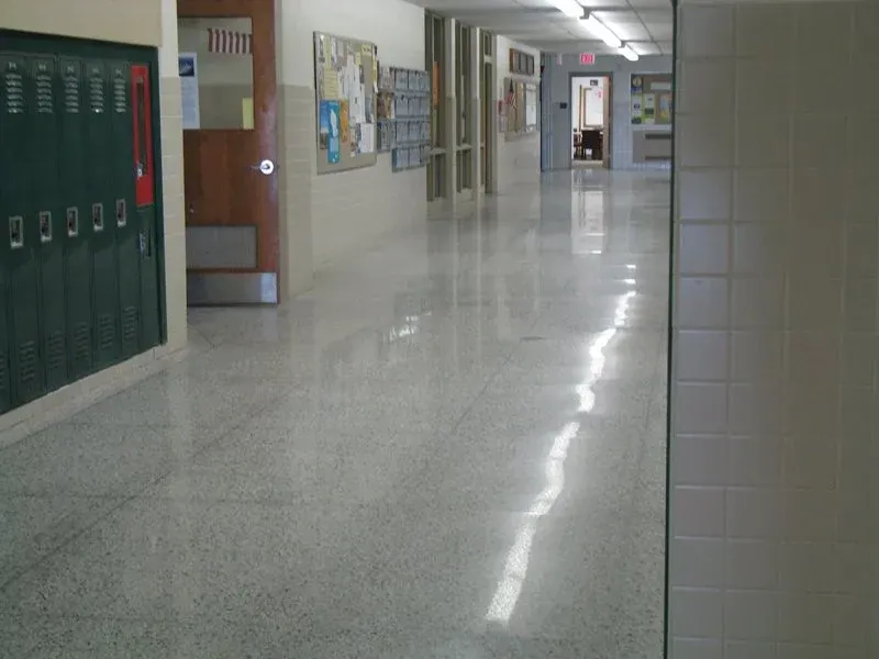 Empty school hallway with green lockers and shiny tile floor