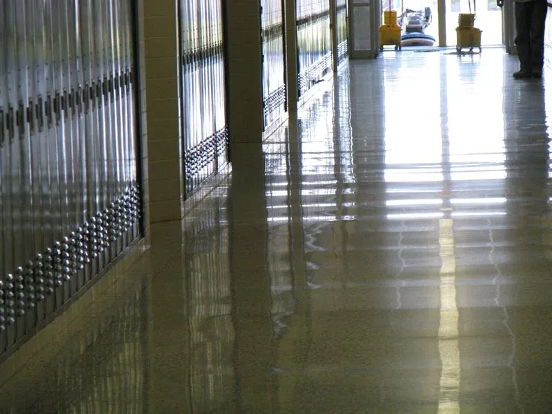 Empty school hallway with shiny tiled floor and lockers along the left side