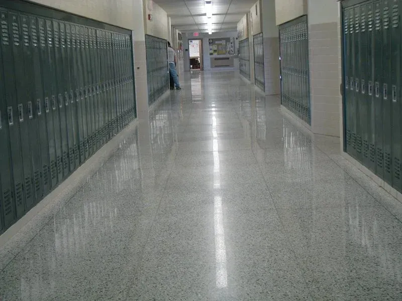Empty school hallway with green lockers and shiny tiled floor