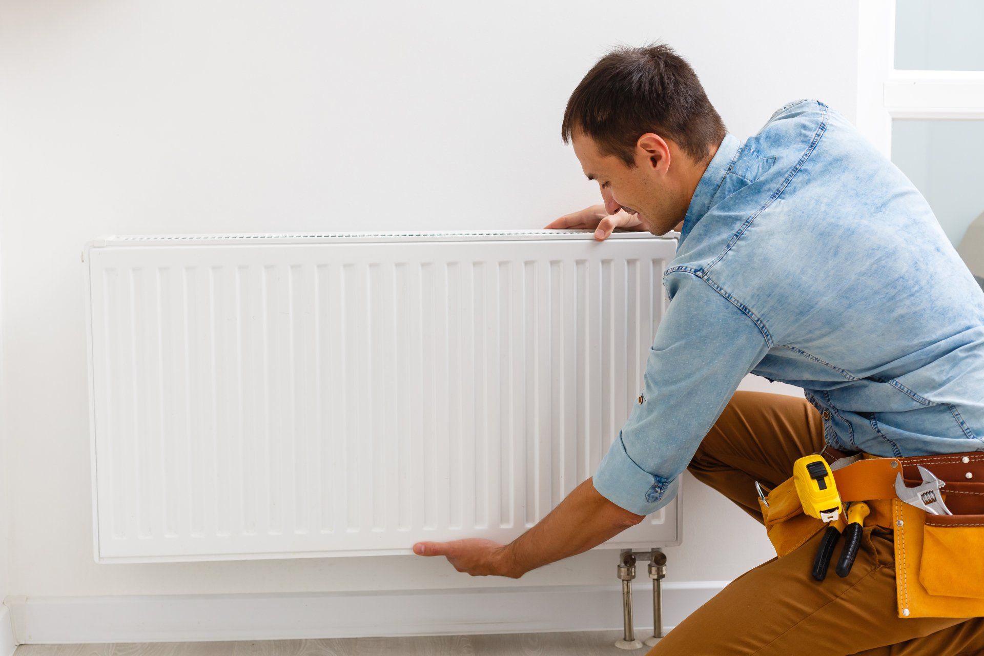 Un homme installe un radiateur dans une pièce.
