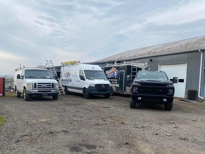 Trois camionnettes et un camion sont garés devant un immeuble.