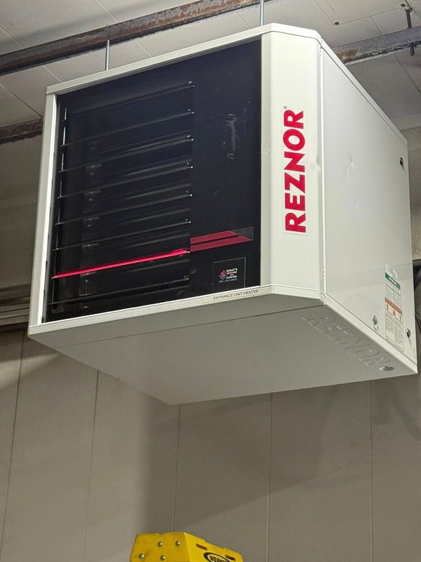 A Reznor commercial unit heater suspended from a ceiling in an industrial setting.