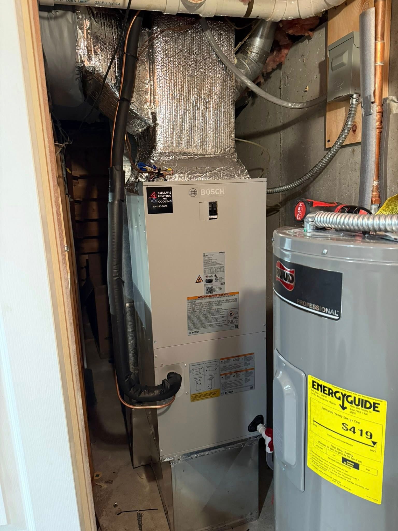An indoor utility closet featuring a tall, gray HVAC air handler unit next to a residential water heater.