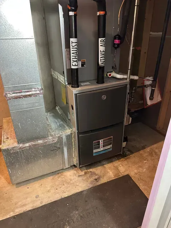 A high-efficiency furnace with two vertical black pipes labeled 