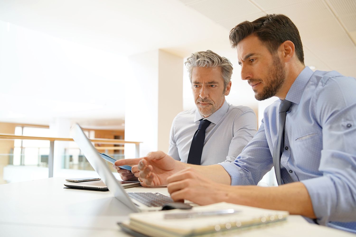 Two coworkers reviewing a laptop at a bright office desk Two coworkers reviewing a laptop at a bright office desk