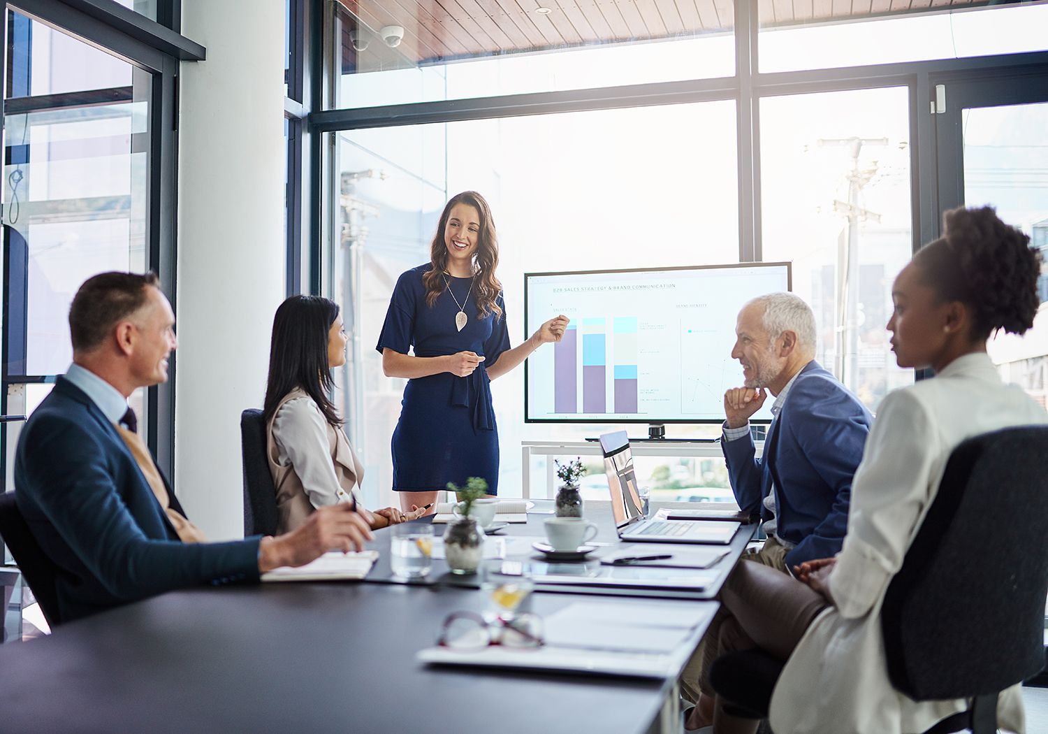 Business meeting with a woman presenting charts to colleagues around a conference table in a bright office
