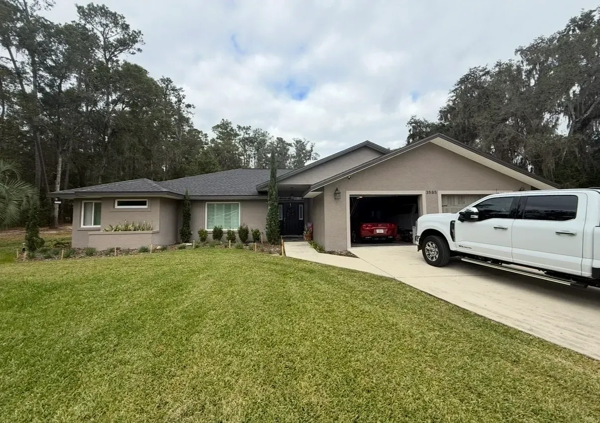 Single-story house with a white pickup truck in the driveway and a red car in the garage.