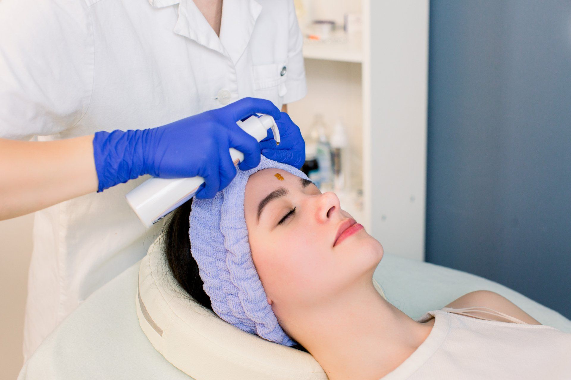 cosmetologist performing facial treatment on woman in spa