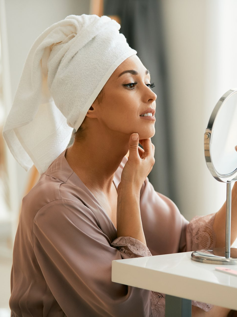 young beautiful woman looking at her face in mirror