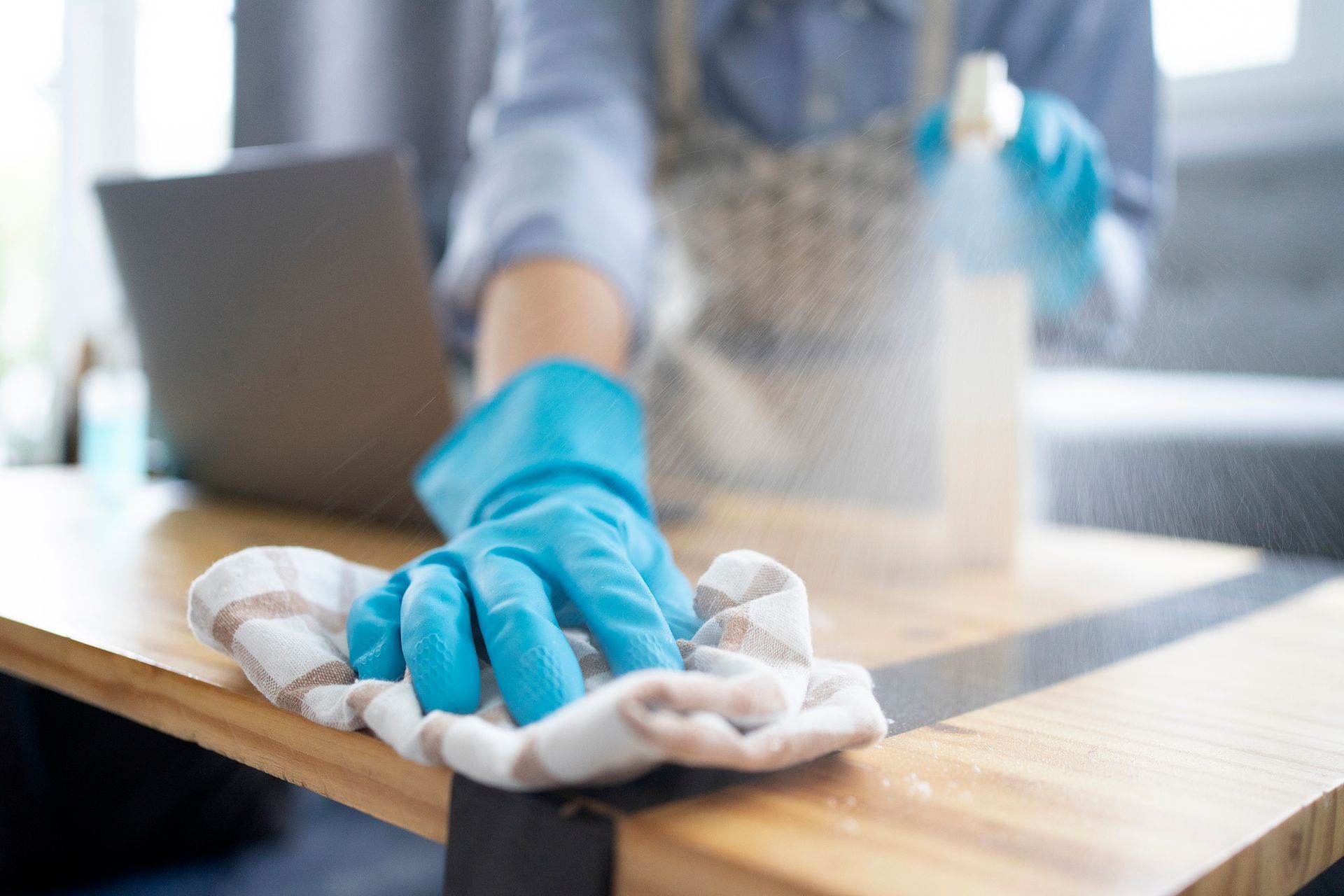 A person is spraying a table with a spray bottle.