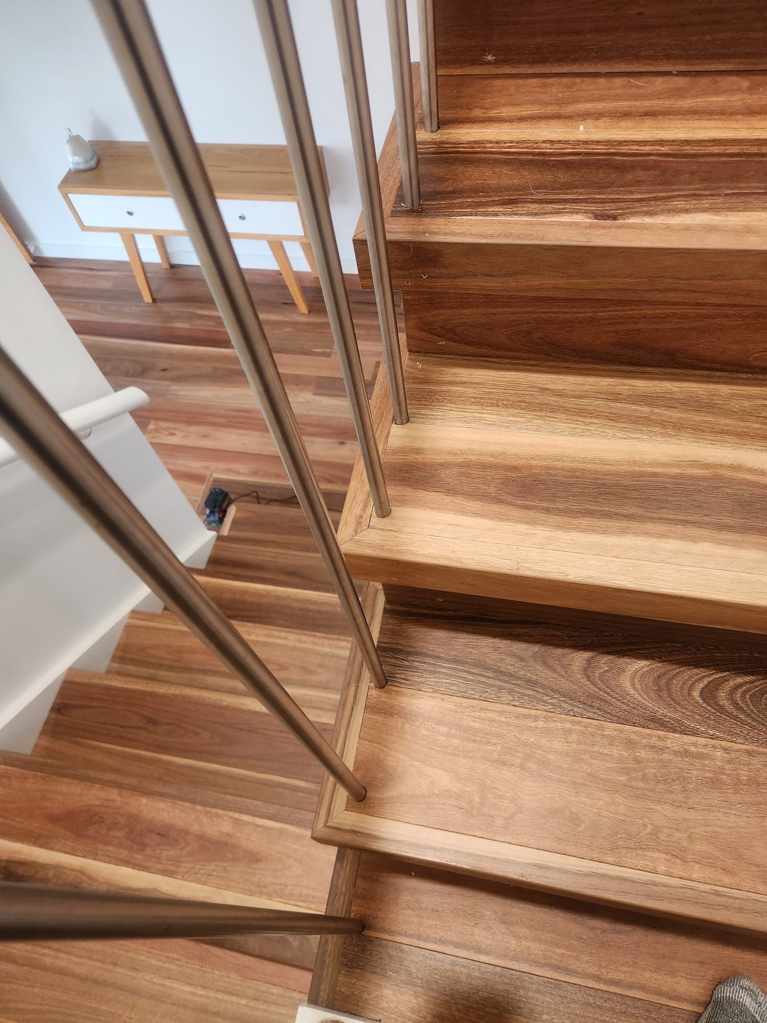 Wooden staircase with metal railing and sunlight on the steps