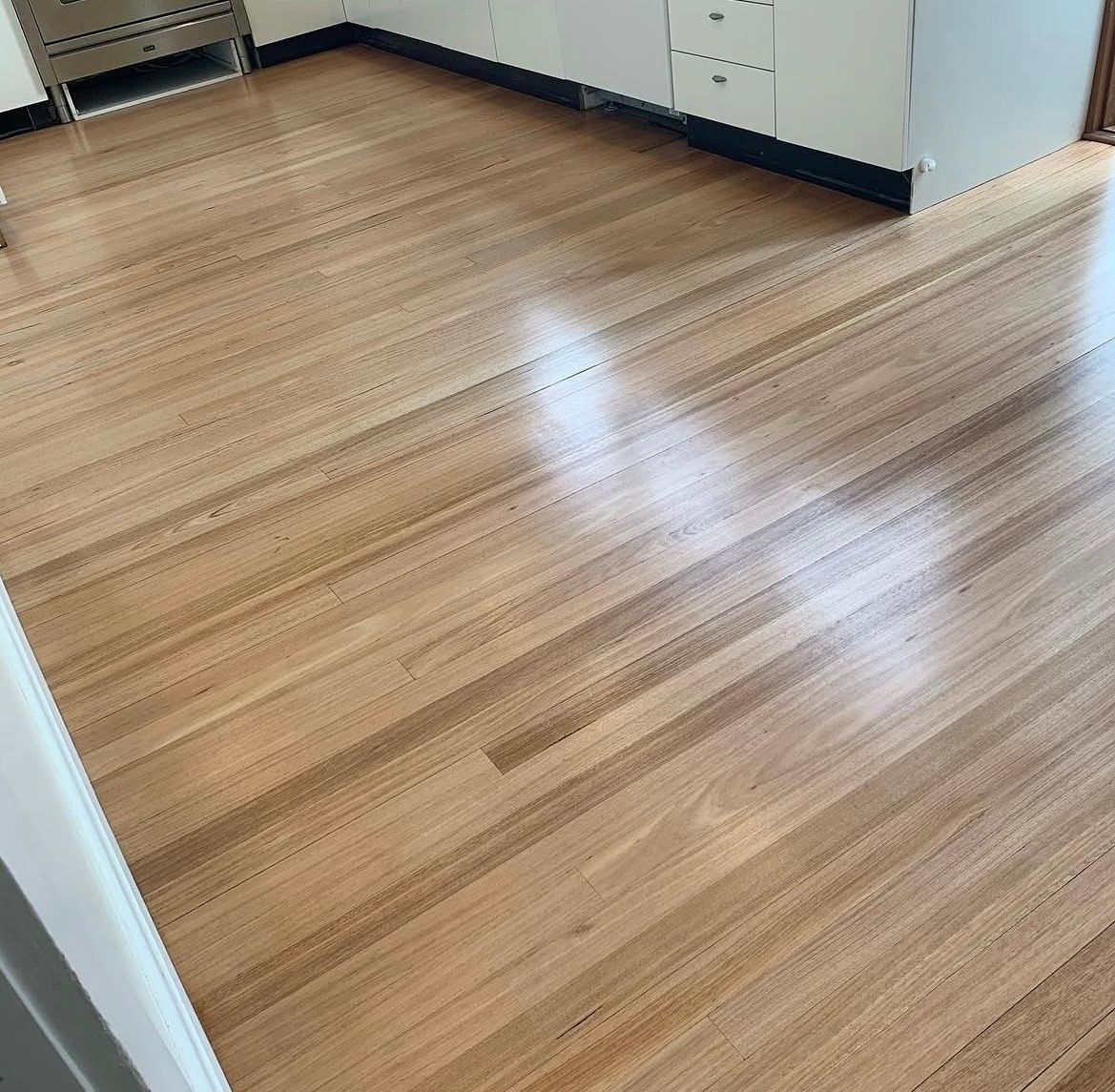 Empty room with light wood flooring and white cabinets along the walls.