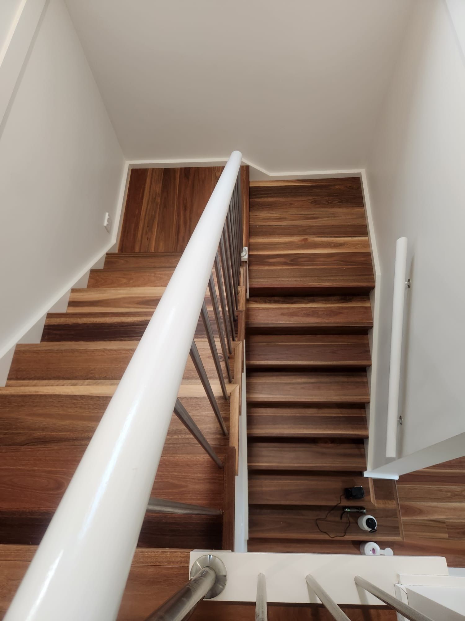 Wooden staircase with white railing in a narrow interior hallway