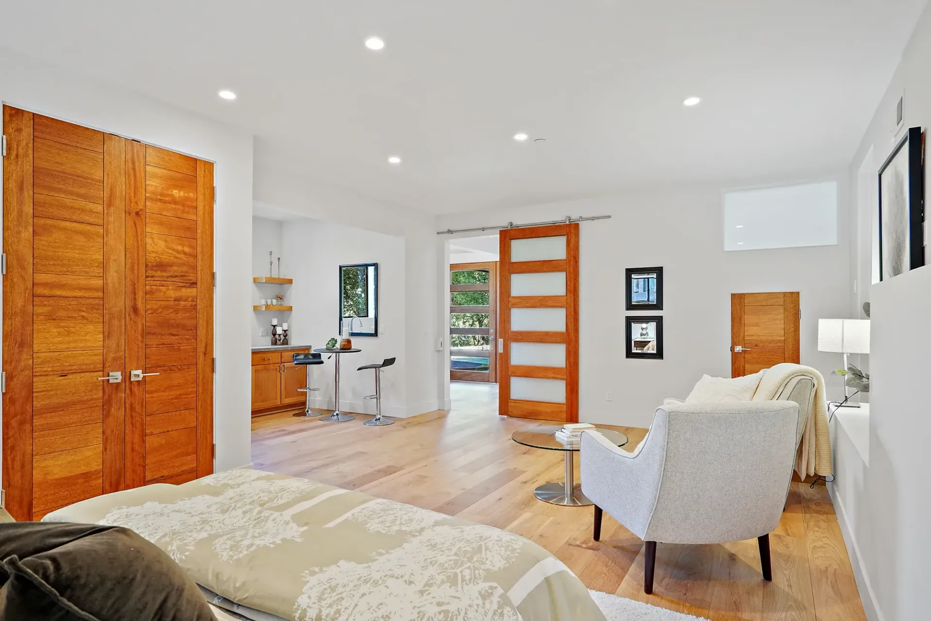 Bedroom with hardwood floors, wooden doors, a chair, and natural light.