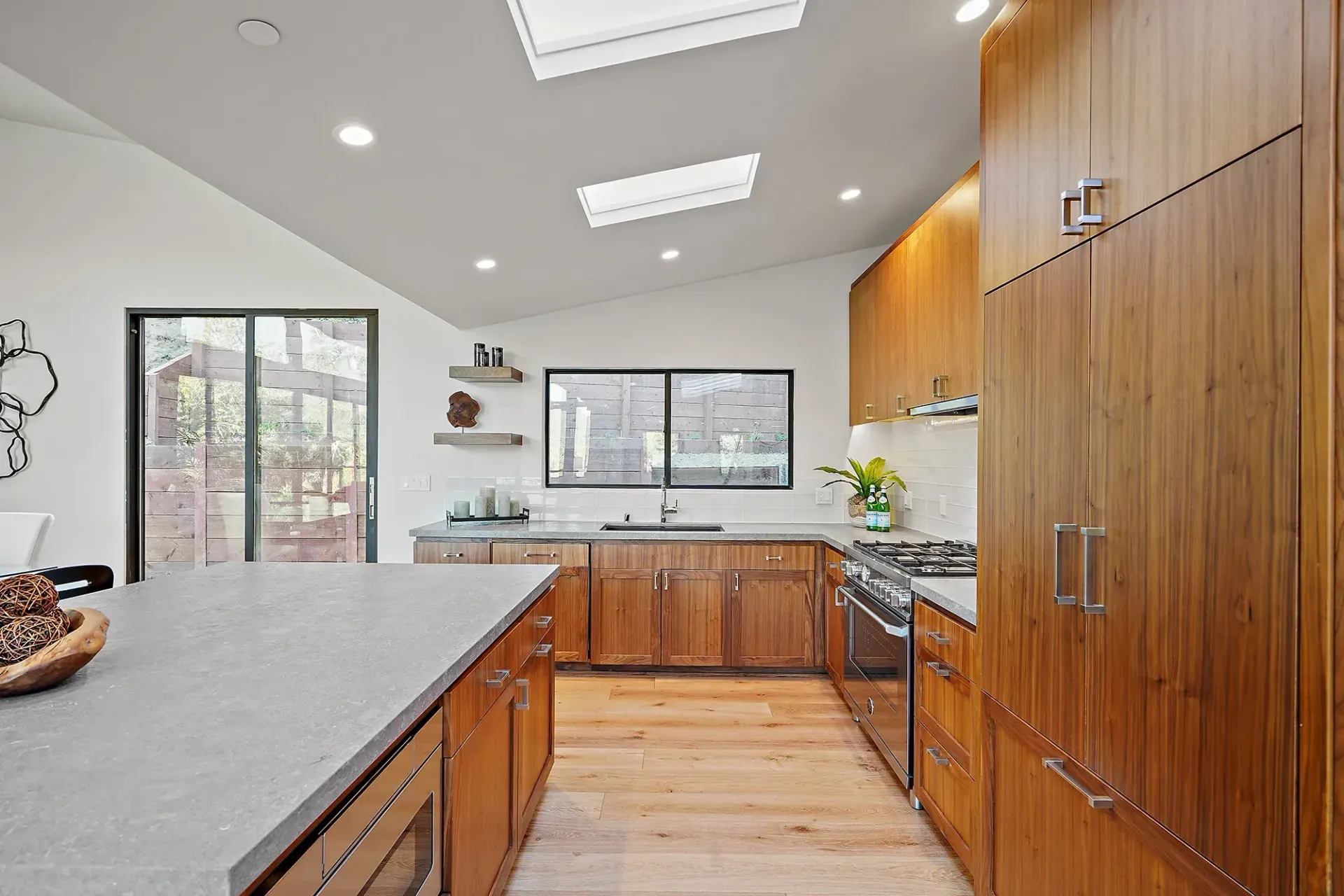 Modern kitchen with wood cabinets, island, and stainless steel appliances.