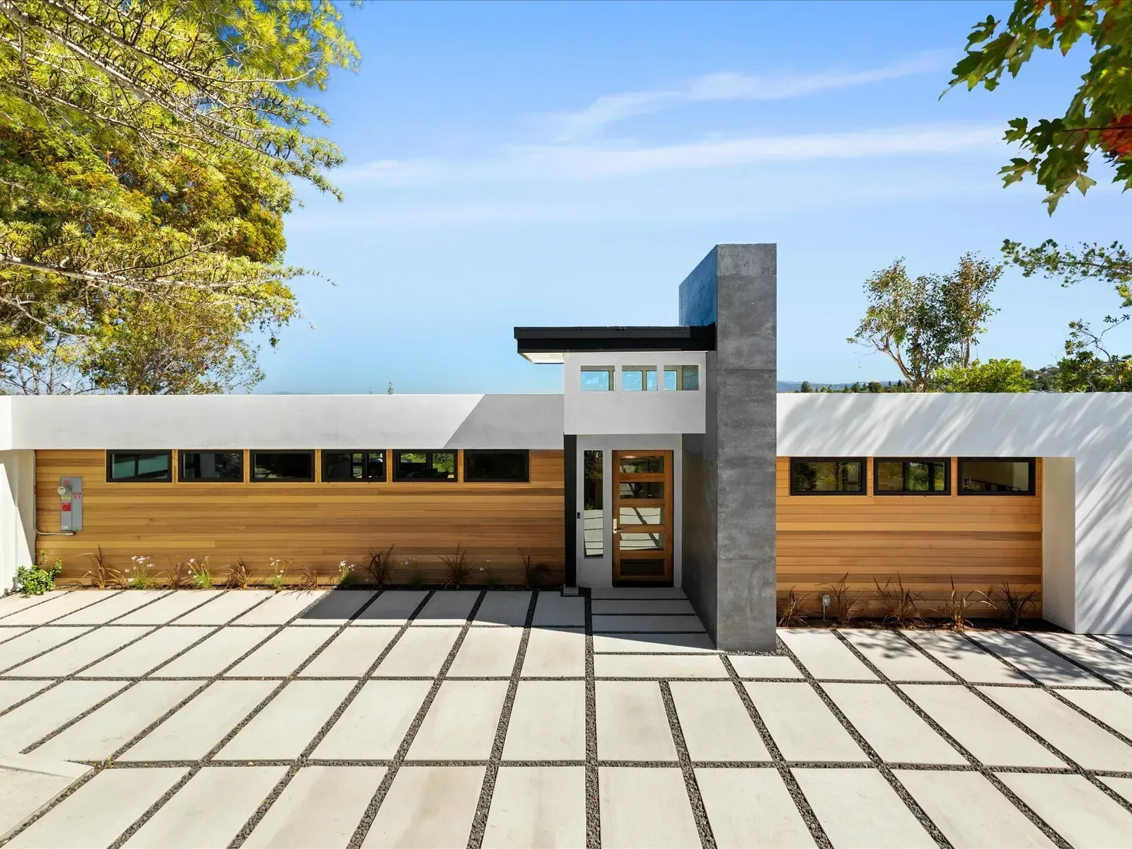 Modern home with wood siding, concrete walkway, and square window panes.