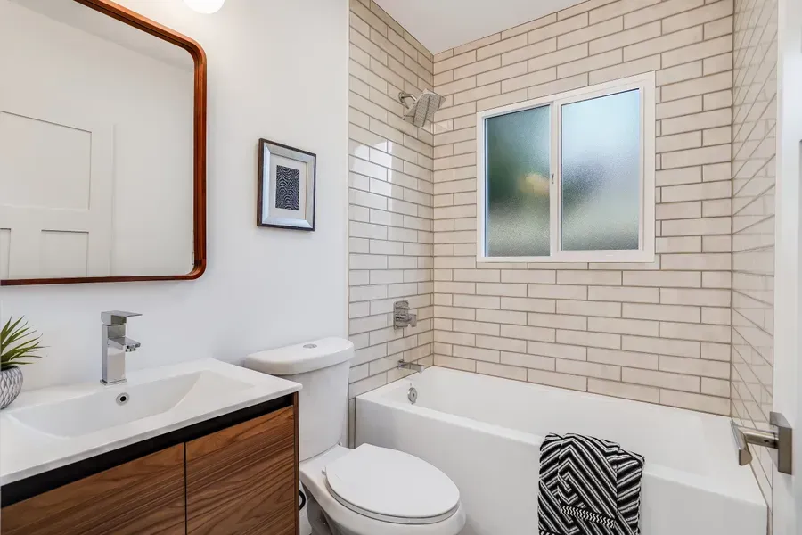 Bathroom with white subway tile, a wooden vanity, and a rectangular mirror.