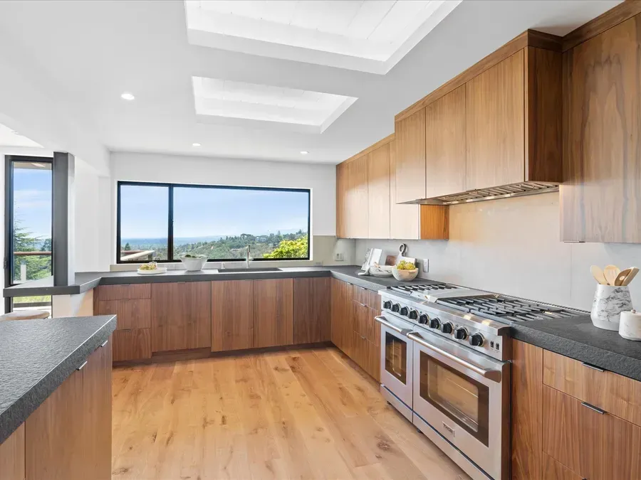 Modern kitchen with wood cabinets, stainless steel appliances, and large window overlooking a scenic view.