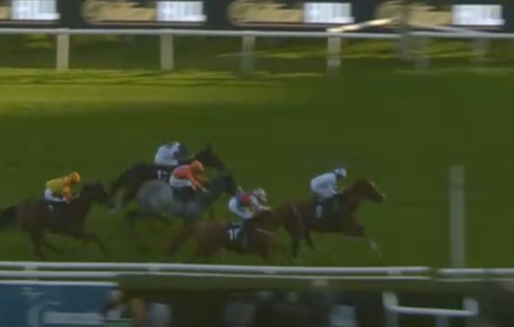 Horses racing on a green track, approaching a numbered marker, riders in colorful silks, sunny day.