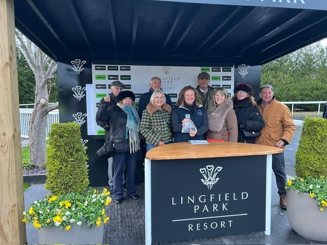 Group posing at Lingfield Park Resort entrance under a canopy, with branded sign and flower displays