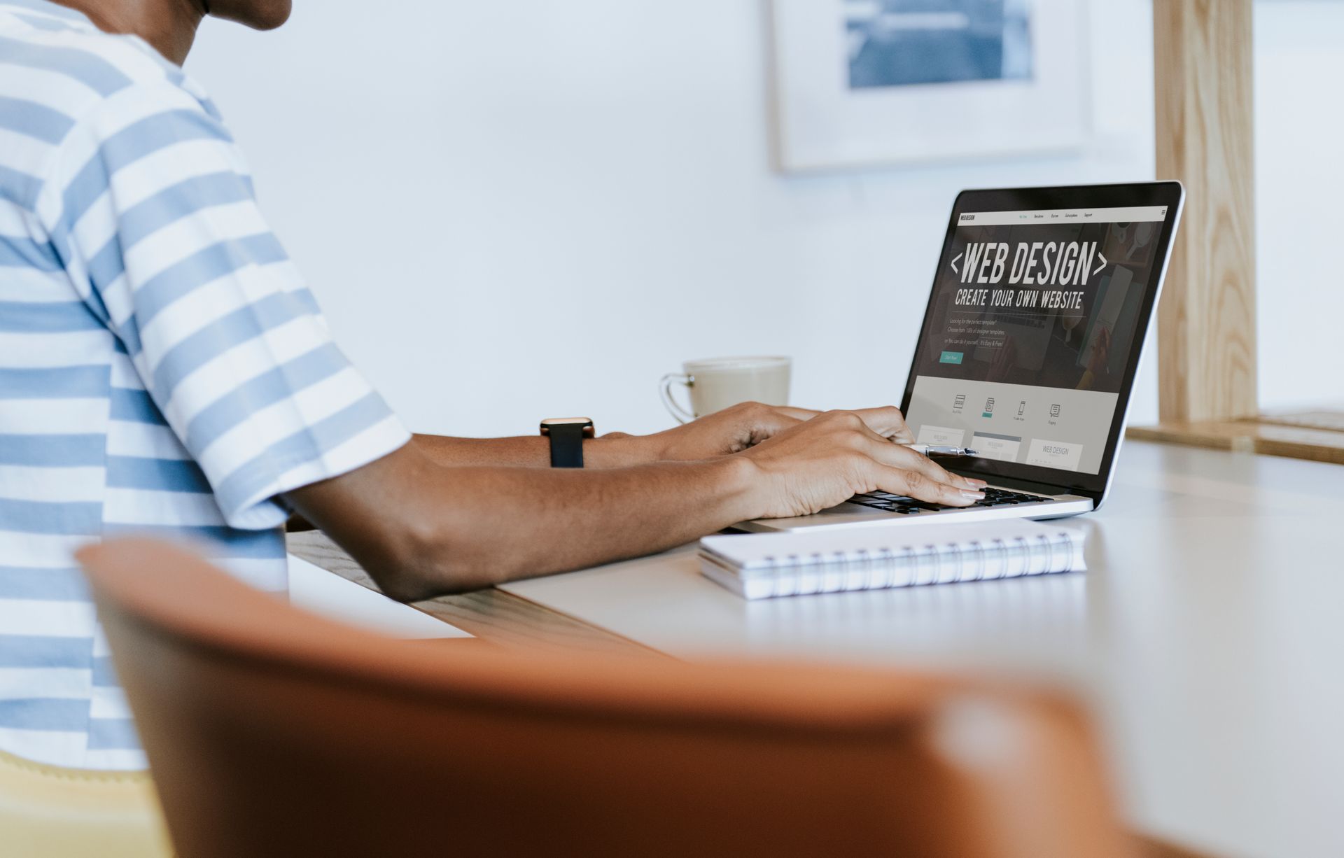 A man is sitting at a table using a laptop computer.