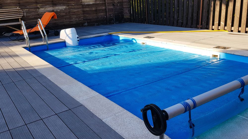 A Swimming Pool With a Blue Cover on It — Solar Services in Gosford, NSW