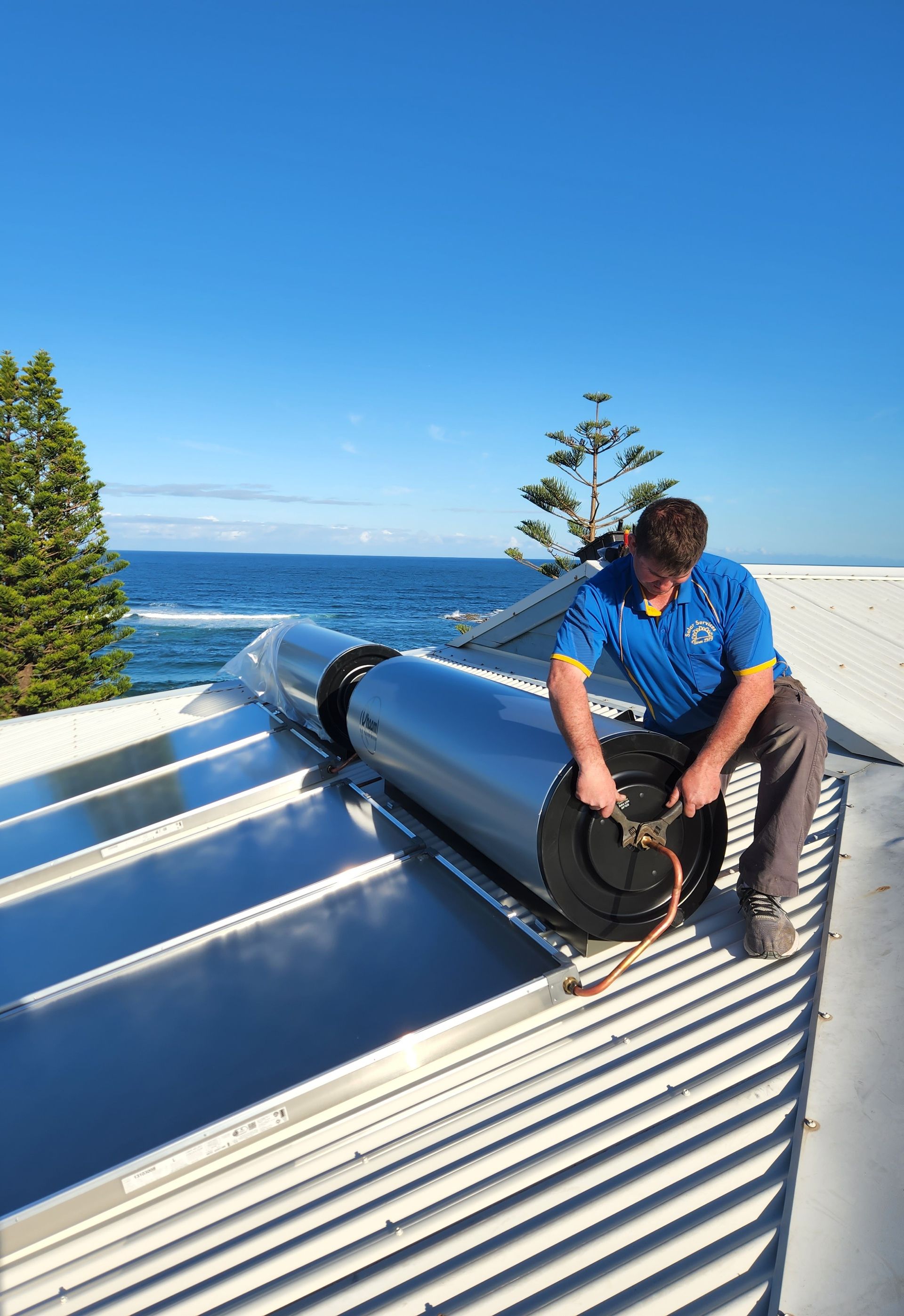 a man on a roof installing a water heating system — Solar Services in Erina, NSW