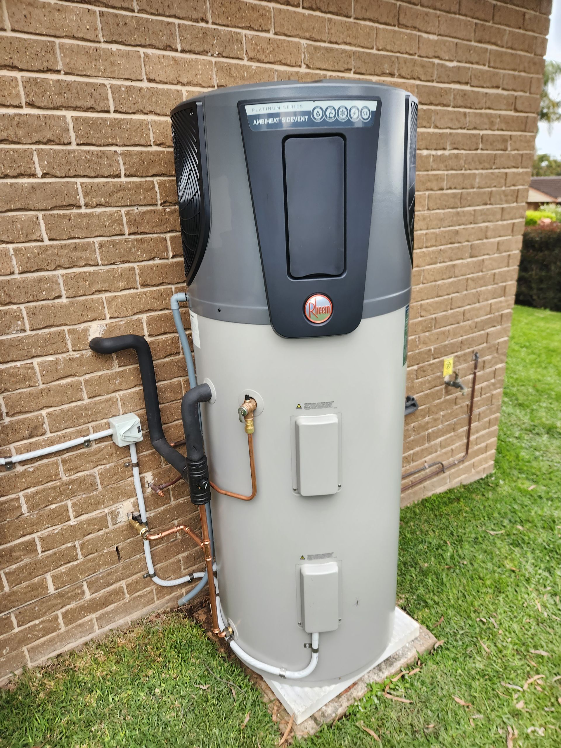 Man installing a heat pump near a pool on a sunny day — Solar Services in Erina, NSW