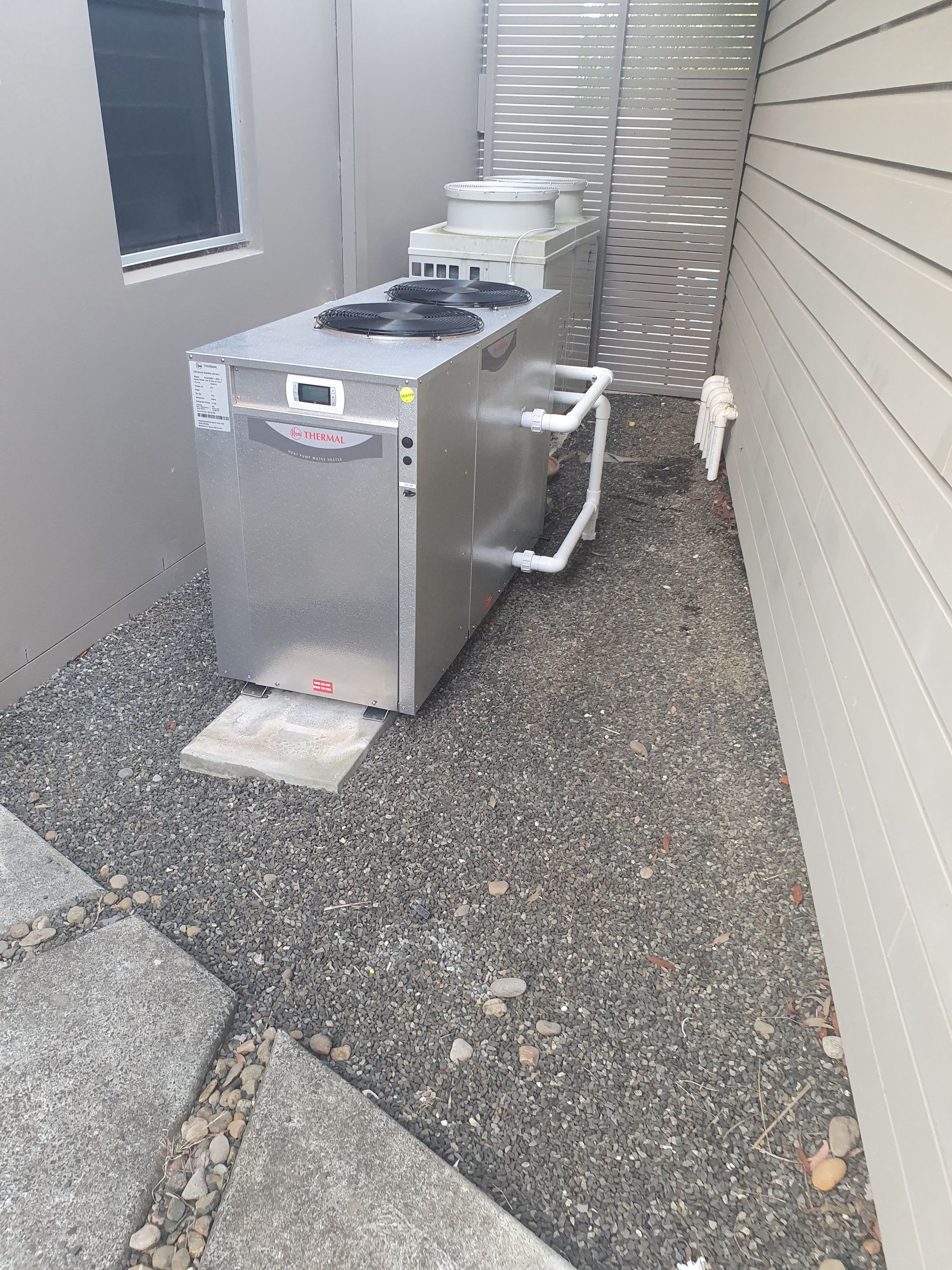 A pool Heater next to a fence on some gravel — Solar Services in Erina, NSW