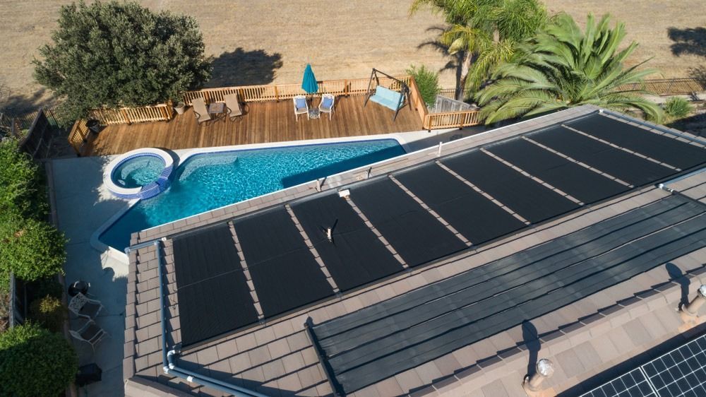 Aerial View Of A Backyard Pool And Rooftop Solar Panels — Solar Services in Erina, NSW
