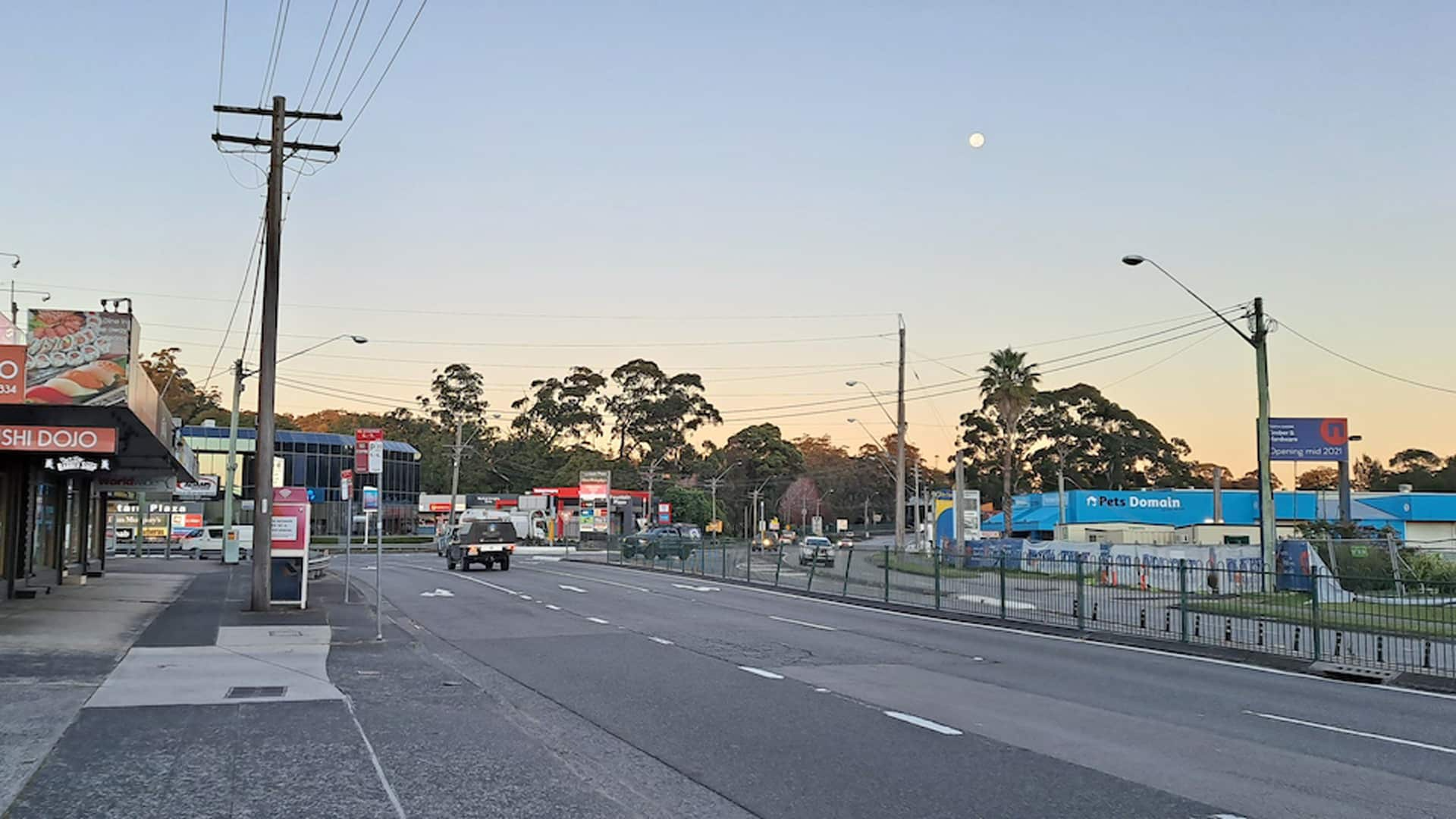 An Empty Parking Lot With Palm Trees in Front of a Building — Solar Services in Erina, NSW