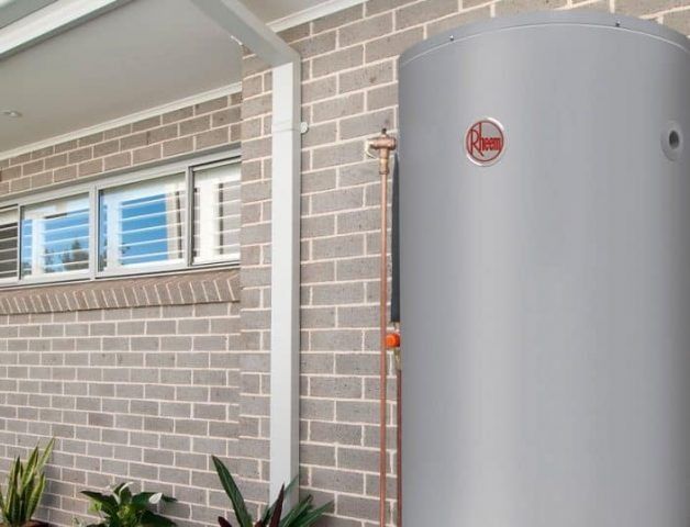 A Gray Water Heater is Sitting on the Side of a Brick Building — Solar Services in Terrigal, NSW