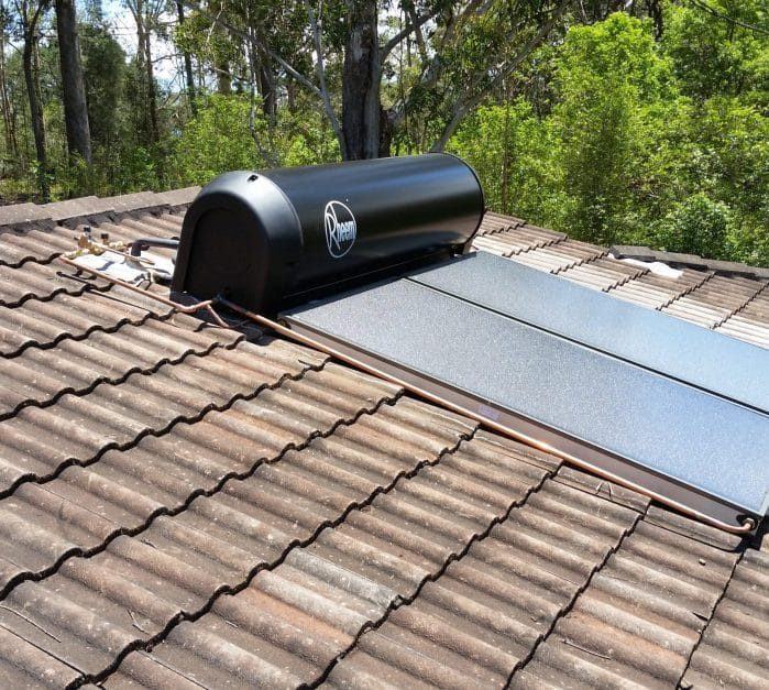 A House With Solar Panels on the Roof and Trees in the Background — Solar Services in Erina, NSW