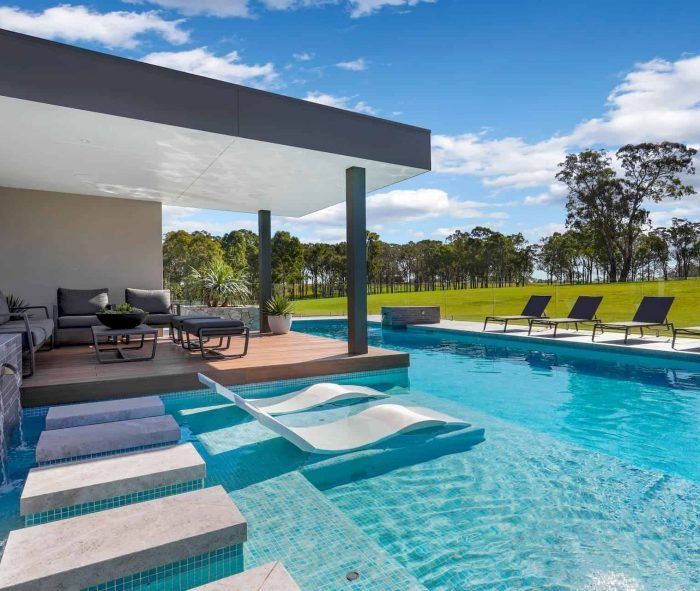 A Large Swimming Pool Surrounded by Chairs and a Patio — Solar Services in Erina, NSW