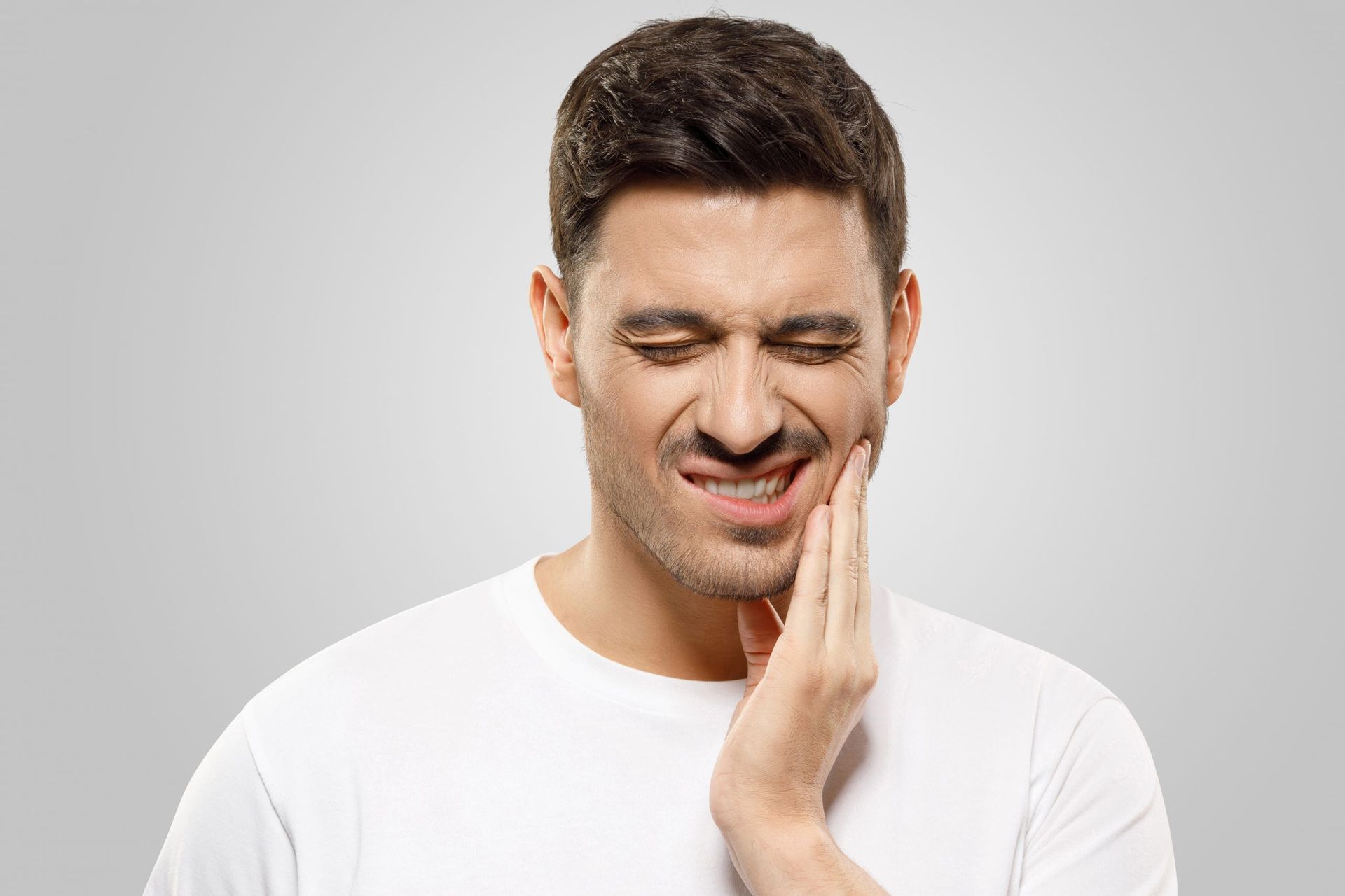 Un uomo si tiene il viso dolorante a causa del mal di denti.