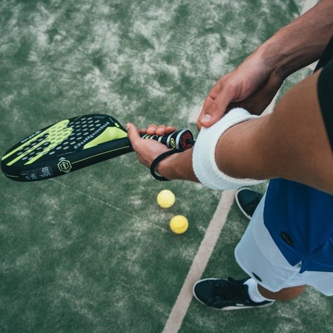 Una persona tiene in mano una racchetta da tennis su un campo da tennis