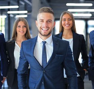 Three smiling professionals in business attire walking through a modern office corridor