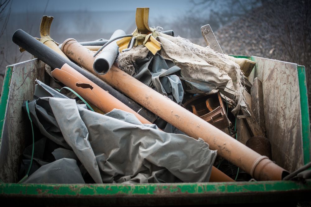 Green Dumpster Filled With Construction Debris: Pipes, Fabric, and Wood — Hasti Skips in Brunswick Heads, NSW