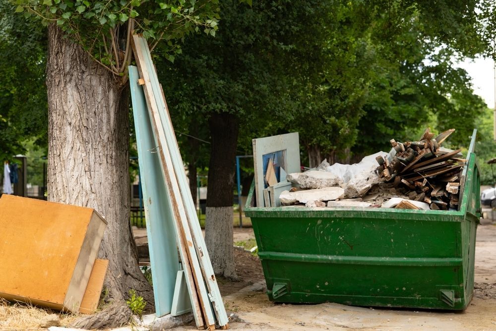 Green Dumpster Overflowing With Construction Debris Lumber, Wood, and Concrete — Hasti Skips in Alstonville, NSW