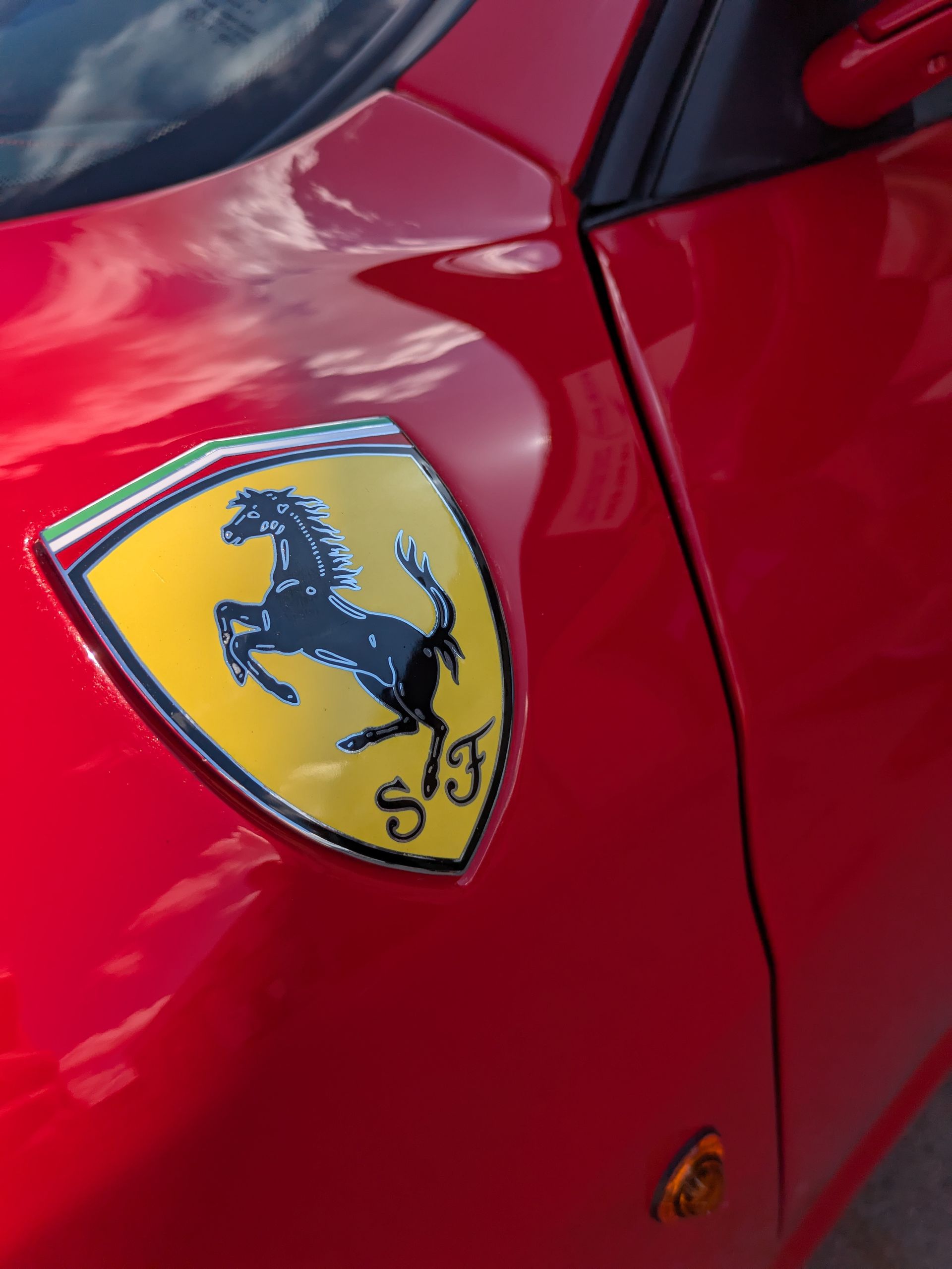 Ferrari emblem on a red car, featuring a black horse on a yellow shield.