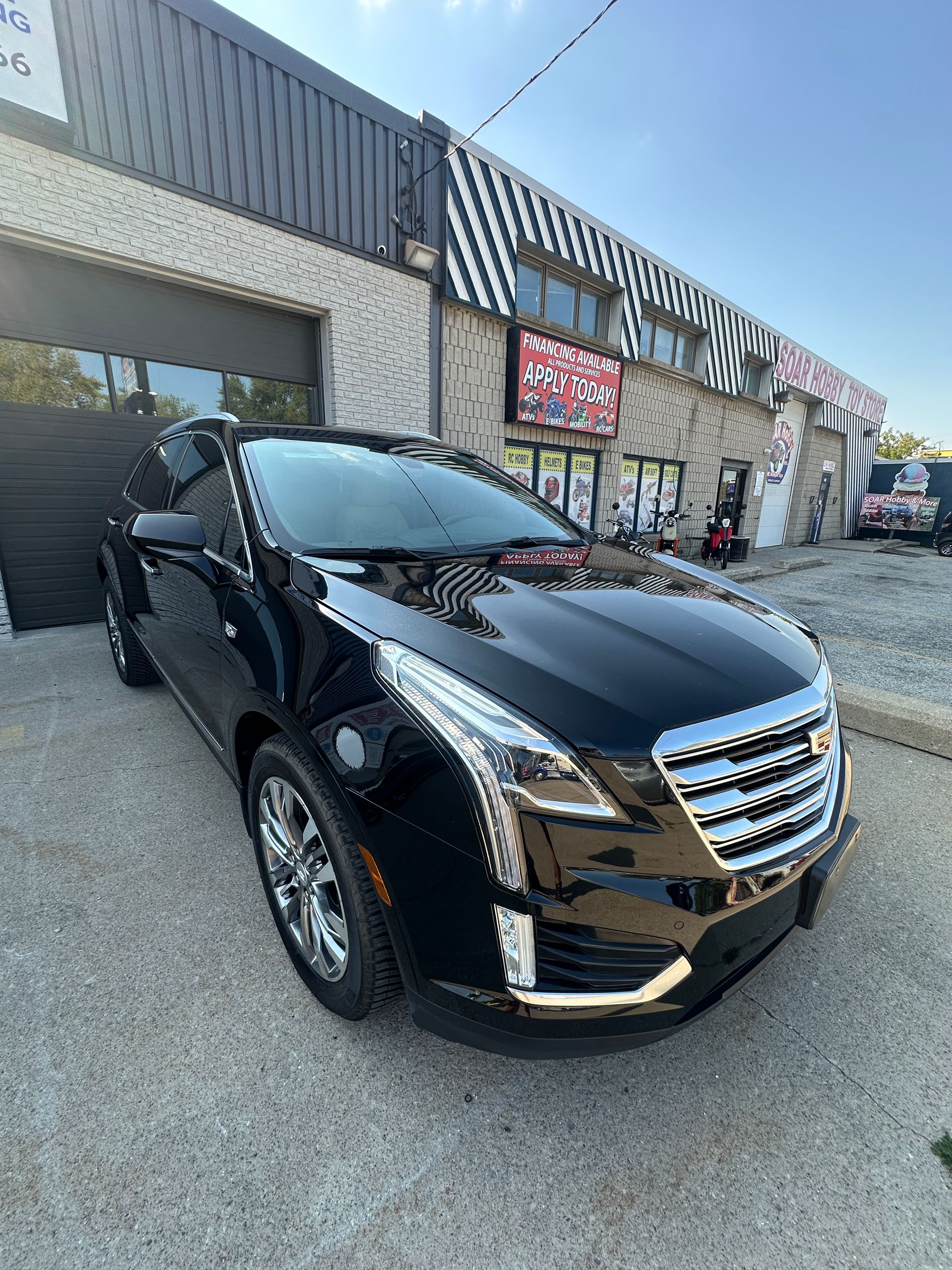 Black SUV parked outside a storefront in a commercial lot