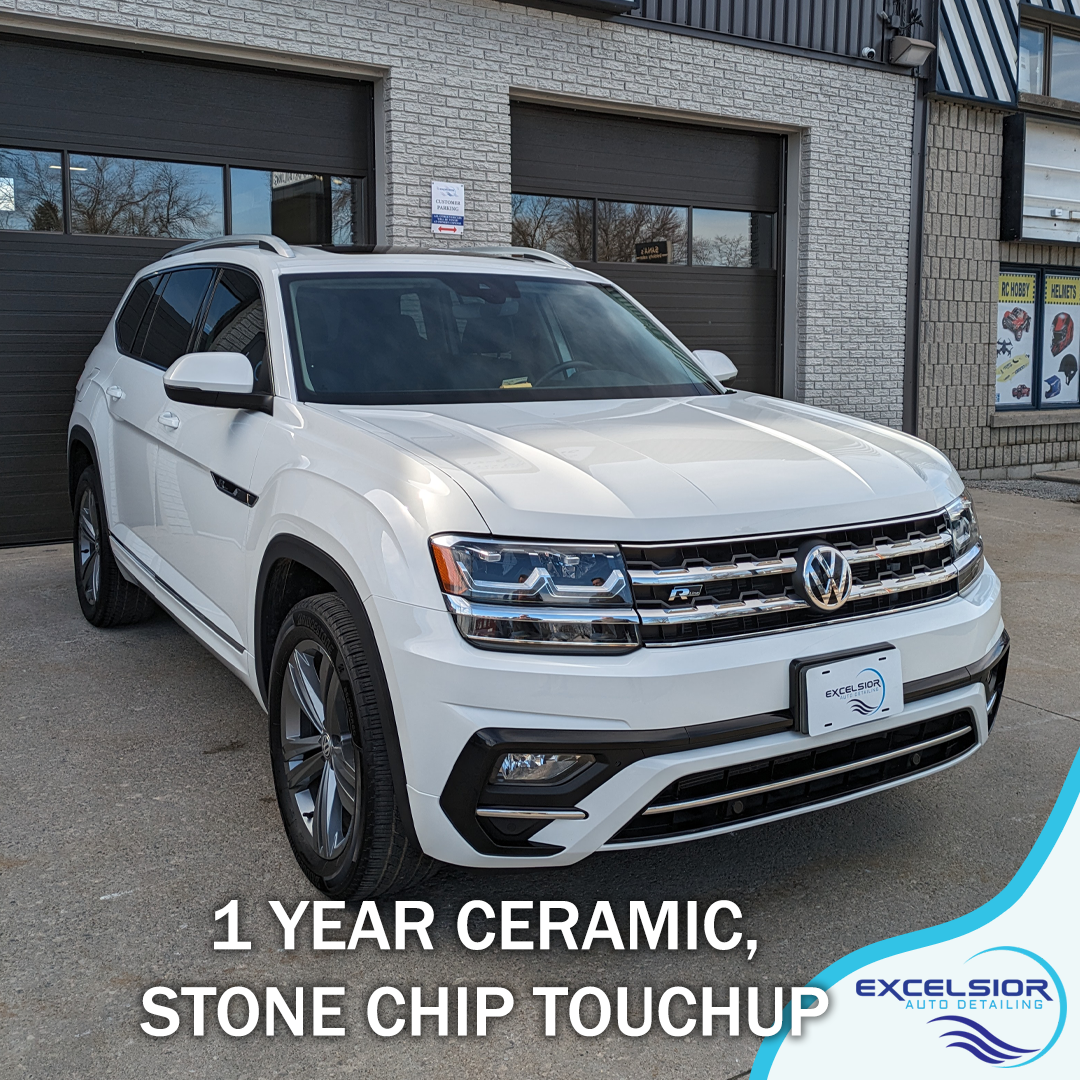A white volkswagen atlas is parked in front of a garage.